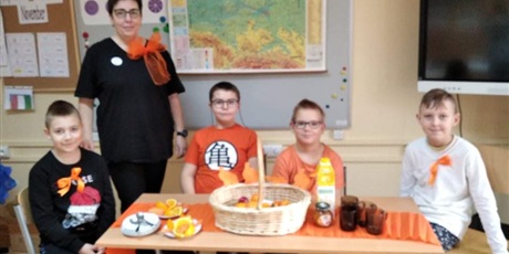 Powiększ grafikę: Uczniowie klasy 3 oraz pani Magda przygotowują śniadanie w kolorze pomarańczowym.